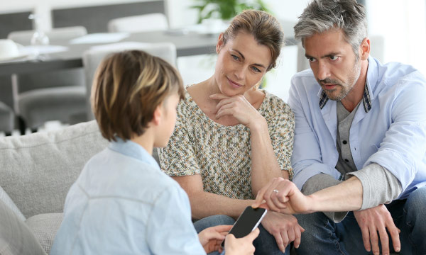 Familie schaut gemeinsam auf einen Smartphone-Bildschirm auf einem Sofa