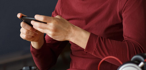 Person using a smartphone with headphones nearby